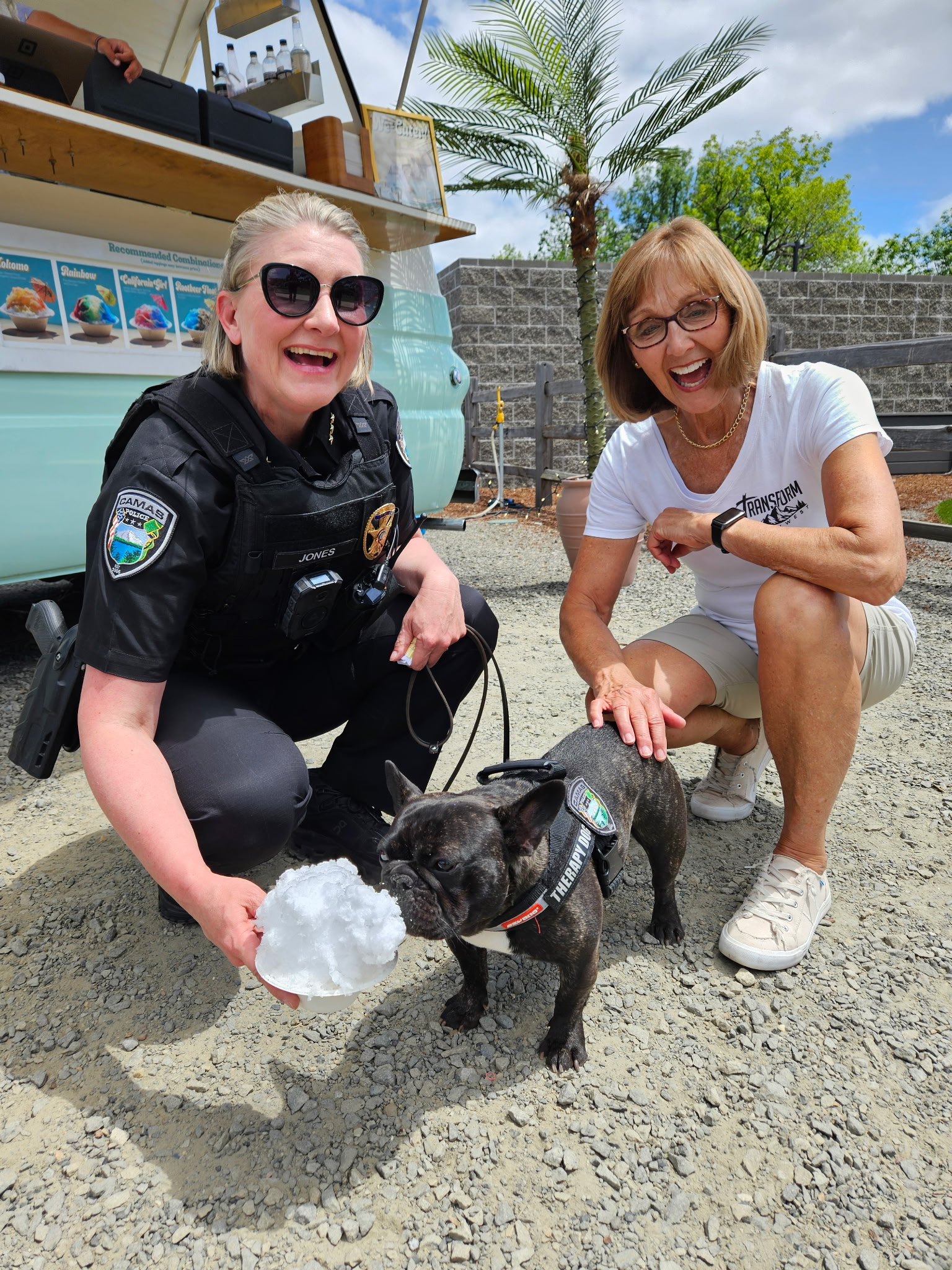 A Camas police officer and Transform Northwest volunteer with a dog enjoying a frozen treat